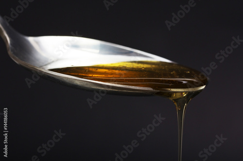 Honey pouring from spoon against a dark background