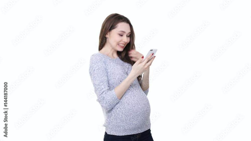 Young pregnant woman using mobile phone and receiving good news isolated over white Young pregnant woman using mobile phone and receiving good news isolated over white
