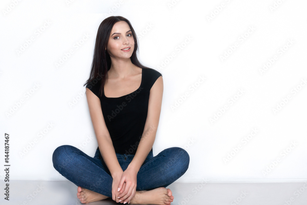Barefoot woman in casual wear sitting on floor Barefoot woman in casual wear sitting on floor