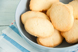 A group of butter shortbread cookies in a bowl on white wooden background. Selective focus. Close up.
