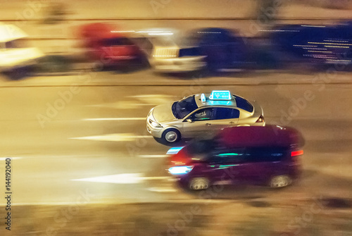 Taxi in the nocturnal streets, rushing through the city, panning photo