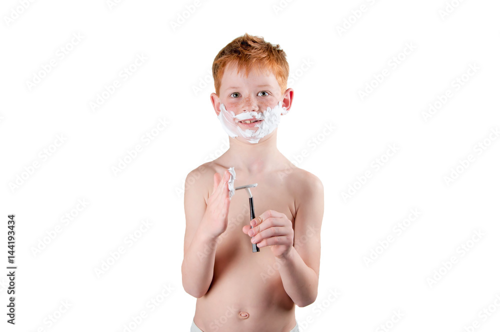 boy redhead with freckles naked to the waist, playing with the razor and foam isolated on white.