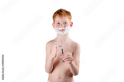 boy redhead with freckles naked to the waist, playing with the razor and foam isolated on white.