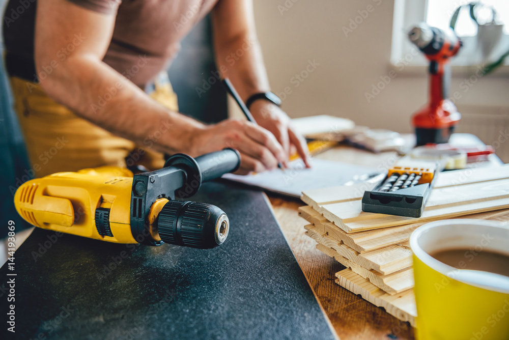 Power drill and Man making draft plan in the background Power drill and Man making draft plan in the background
