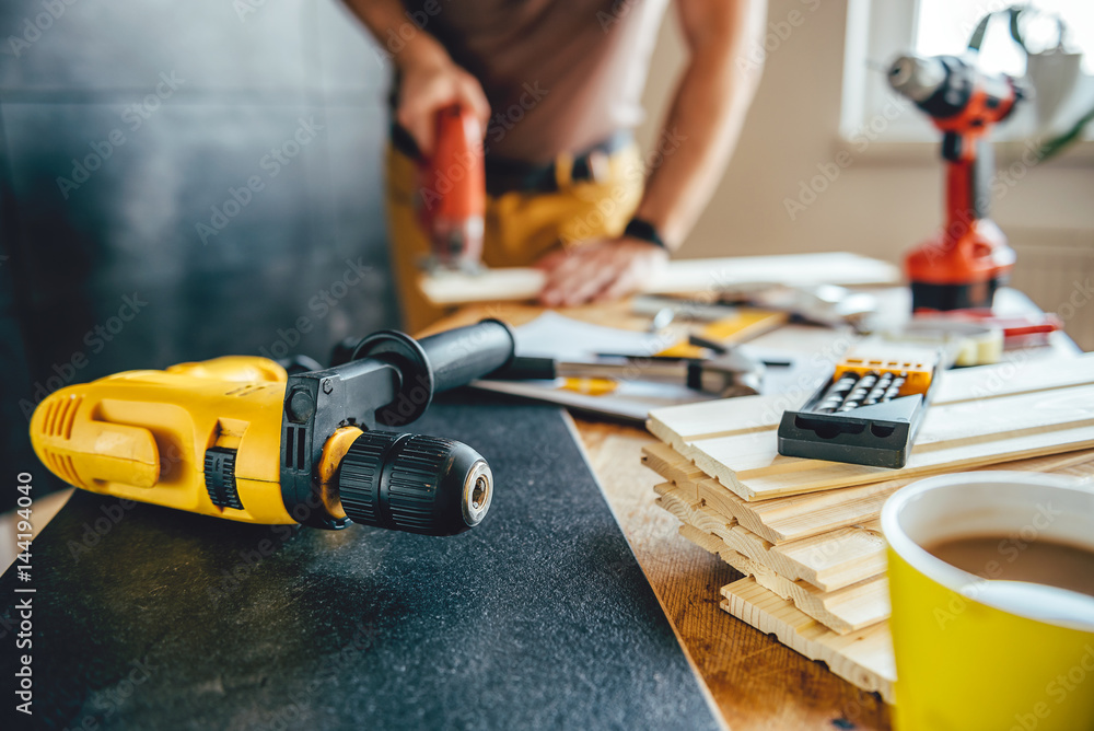 Power drill and Man using electric Jigsaw in the background Power drill and Man using electric Jigsaw in the background