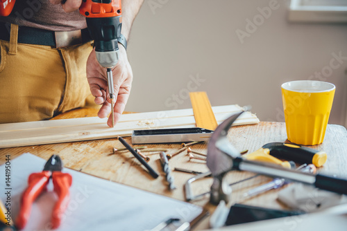 Man Screwing A Screw Into Wood photo