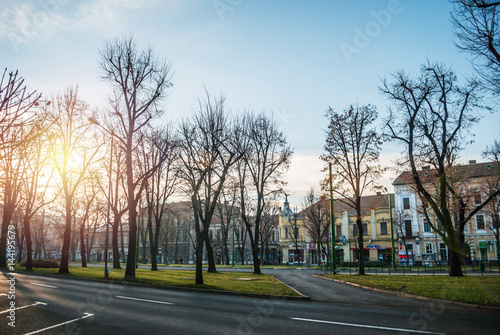 Arad, Romania - January 01, 2013: Park in the city of Arad, Romania, with buildings in the background and a strong sun which sets