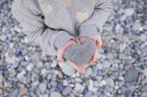 a stone in the shape of a heart in children's hands