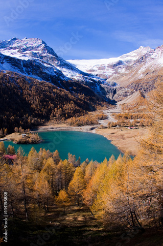 The lake of Alp Grum surrounded by autumn colors, in the background glacier PalÃ¹. Poschiavo Valley Canton of GraubÃ¼nden Switzerland Europe