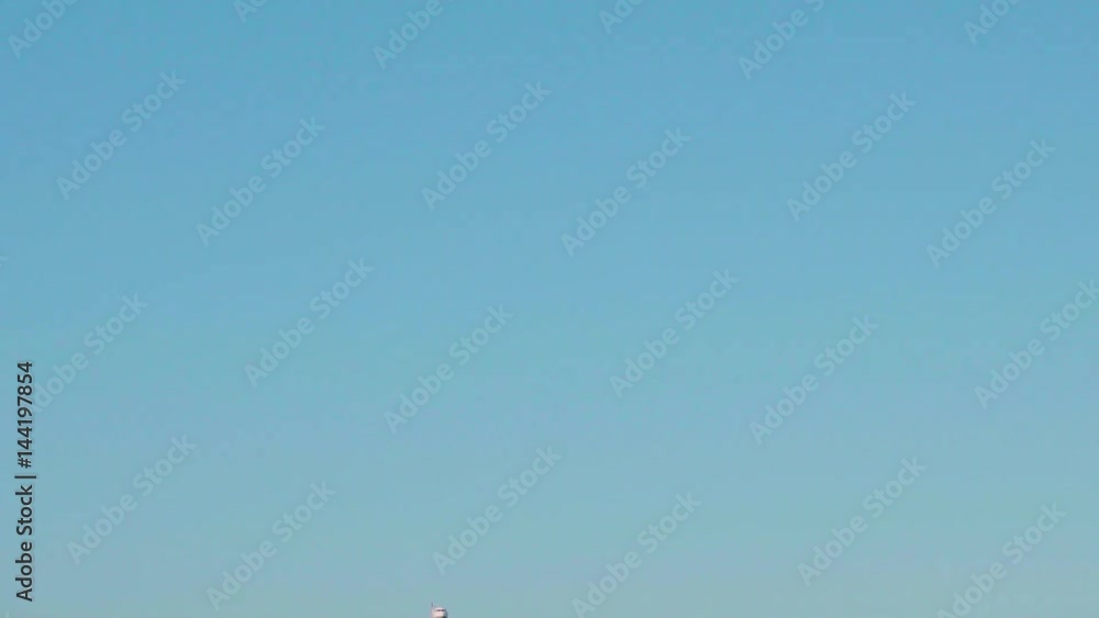 Medium sized white grey air bus with passengers slowly approaching in front and passing over, isolated on blue sky background at sunny day Medium sized white grey air bus with passengers slowly approaching in front and passing over, isolated on blue sky background at sunny day