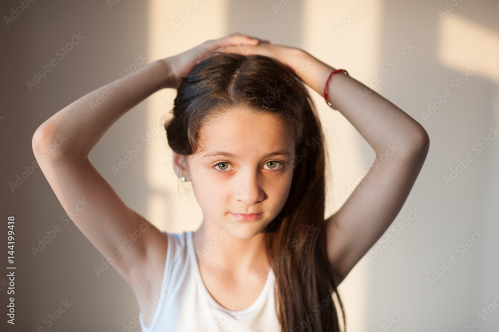 adorable young girl doing her hair with both hands adorable young girl doing her hair with both hands
