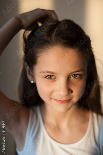 Portrait of smiling little girl adjusting her hair with her hand