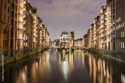 The water castle and buildings are reflected in the canal at dusk PoggenmÃ¼hlenbrÃ¼cke Altstadt Hamburg Germany Europe photo