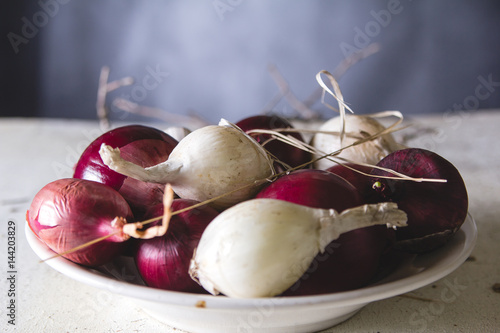 Red and white onion bulbs in the plate on old wooden painted table