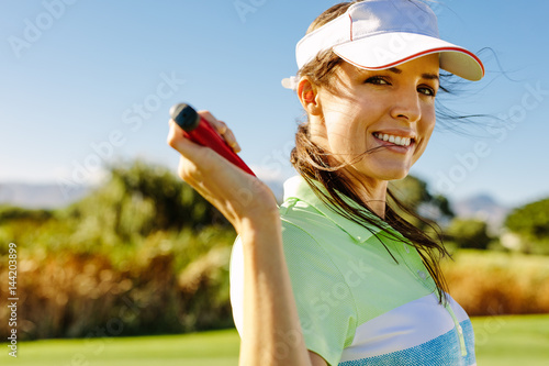 Happy female golfer with golf club on field