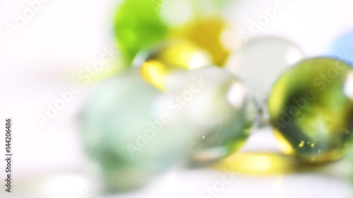 Colorful rolling glass marbles on white background.