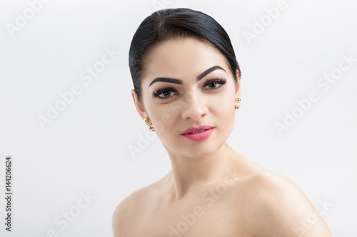 Front portrait of attractive young brunette woman on grey background closeup. girl with clean skin