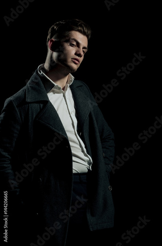 Handsome man posing in white shirt and dark coat