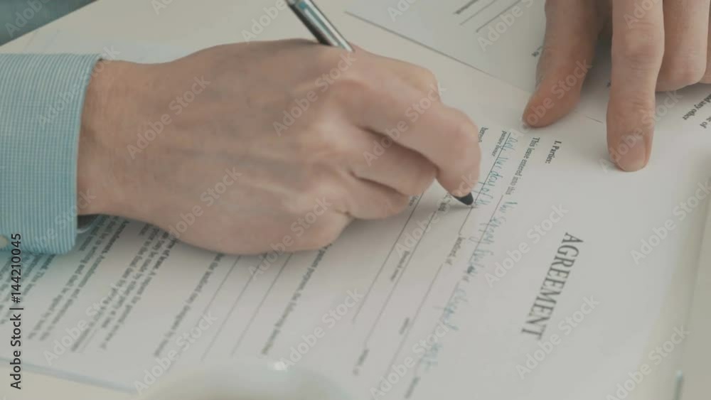 Hand of businessman filling partnership agreement Hand of businessman filling partnership agreement