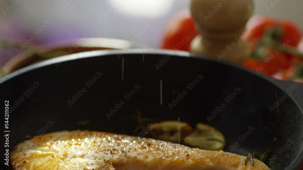 Tilt down slow motion shot of salting salmon steak on frying pan Tilt down slow motion shot of salting salmon steak on frying pan