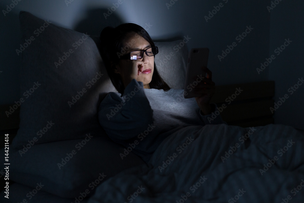 Obraz premium Woman feeling tired when using mobile phone at night