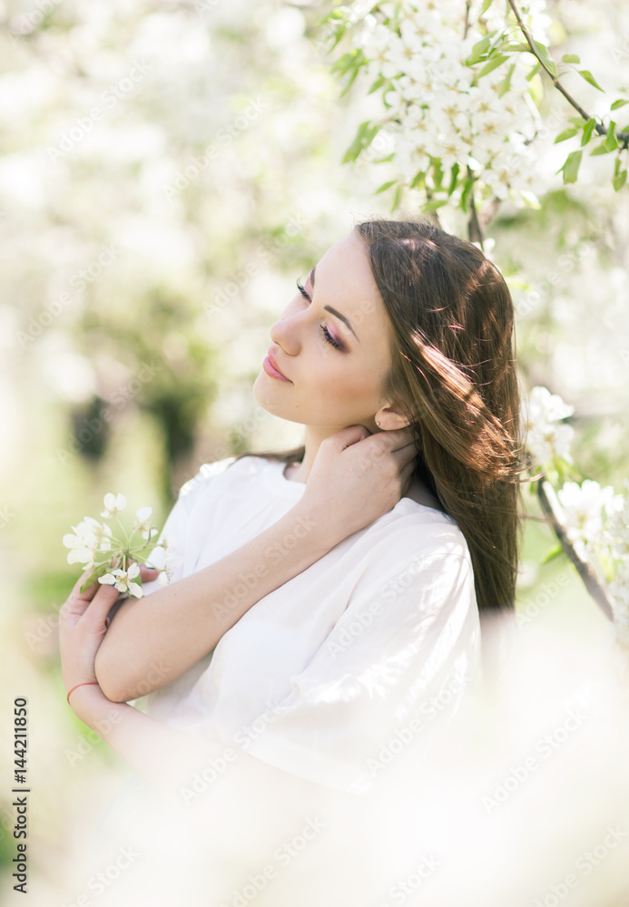 Outdoor Portrait of a Beautiful Brunette Woman in Color dress among Blossom Cherry Trees Outdoor Portrait of a Beautiful Brunette Woman in Color dress among Blossom Cherry Trees