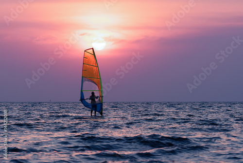 Man playing windsurfing at sunset. © Natnan