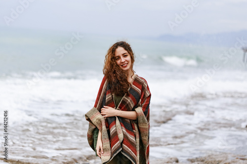 Murais de parede Portrait of happy brunette woman on the beach wearing poncho