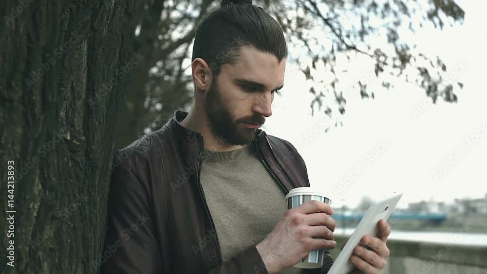 Happy man standing next to the tree and browsing internet on tablet, steadycam shot
Happy man standing next to the tree and browsing internet on tablet, steadycam shot