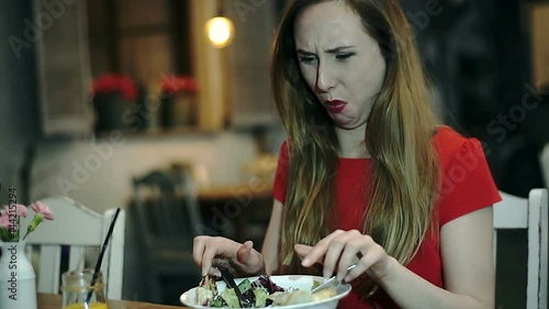Girl looks unhappy while eating disgusting lunch in the cafe
