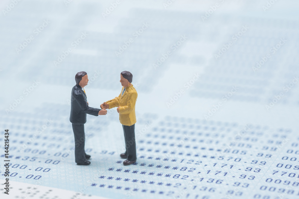 business miniature people shaking hands on book bank background business miniature people shaking hands on book bank background