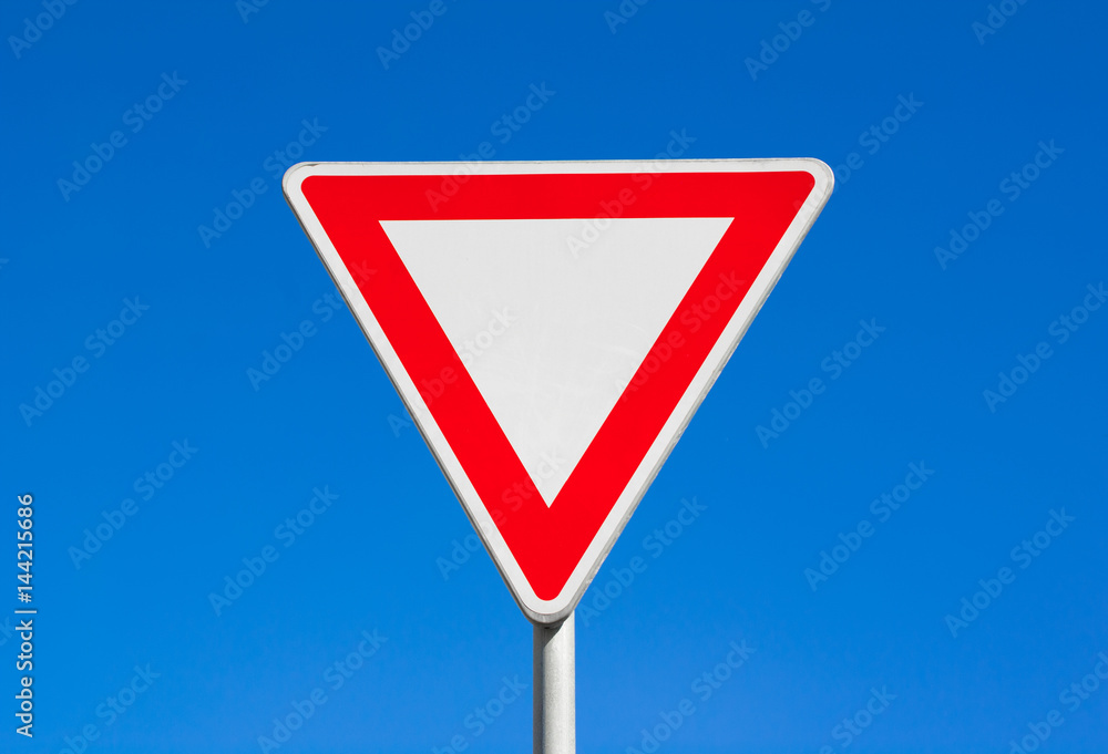 Give way / Yield - red and white triangle. Clear blue sky is behind road sign. - obrazy, fototapety, plakaty 