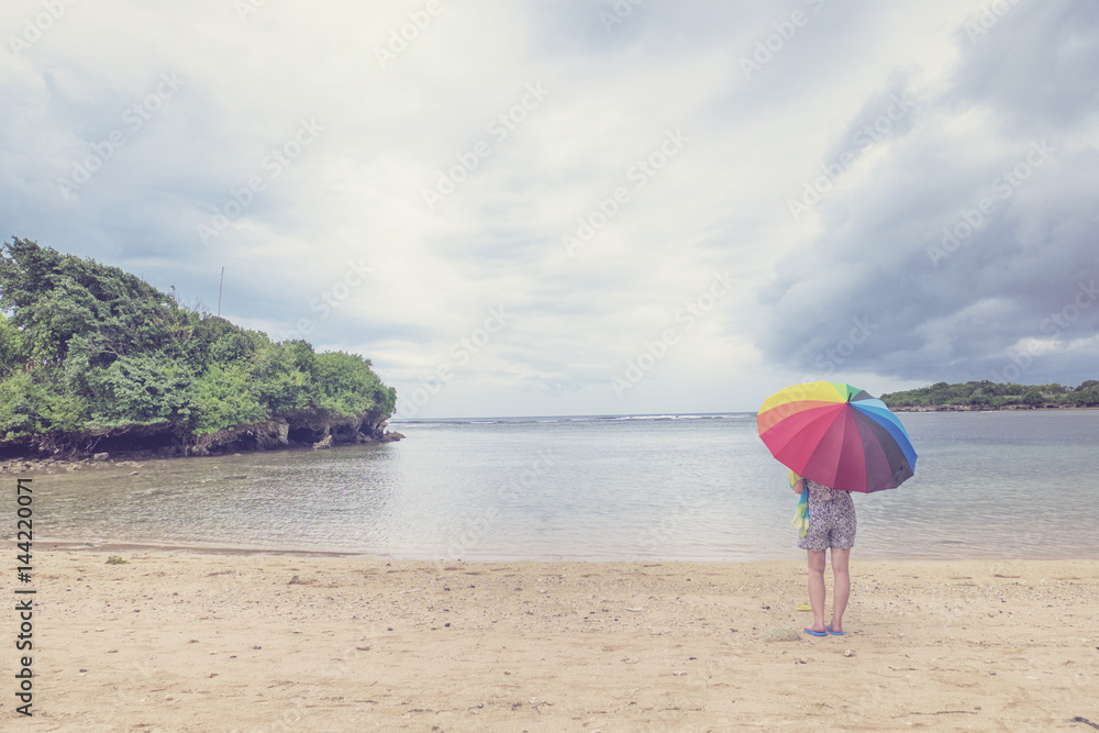 A woman with colorful umbrella on the beach (Hazy)