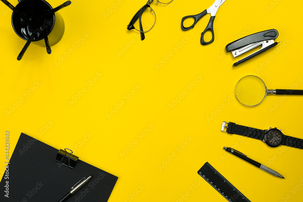 Black objects from the office on a yellow background. Work and creativity. Top view.