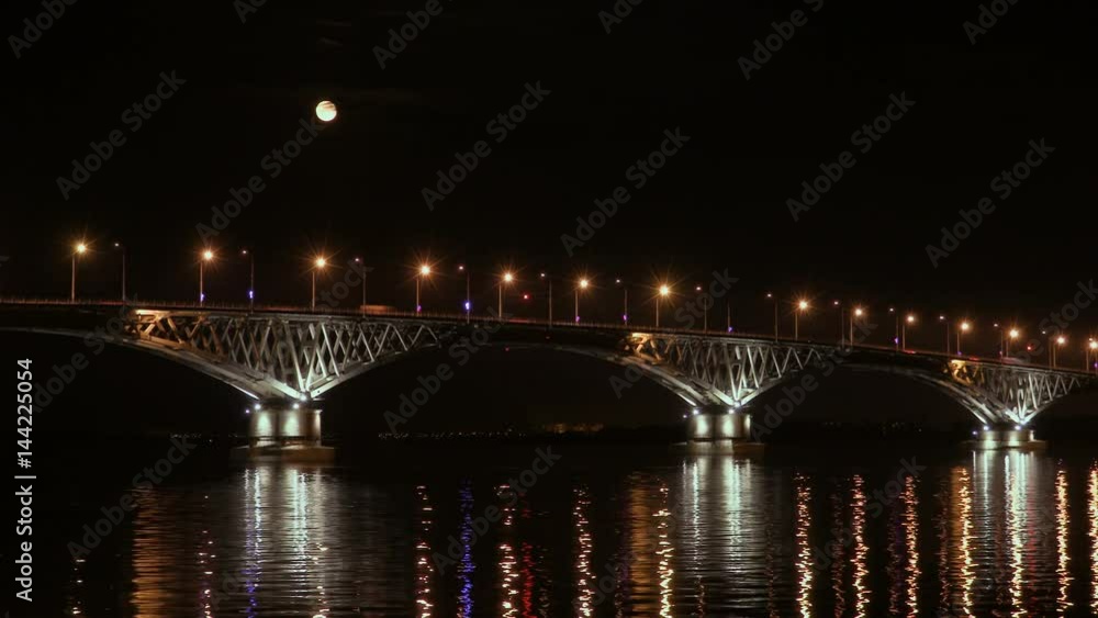 Full moon rises over the bridge. Time-lapse. Road bridge between the cities of Saratov and Engels, Russia. The Volga River. The evening lights of cars and street lights. 4K, Ultra HD Full moon rises over the bridge. Time-lapse. Road bridge between the cities of Saratov and Engels, Russia. The Volga River. The evening lights of cars and street lights. 4K, Ultra HD