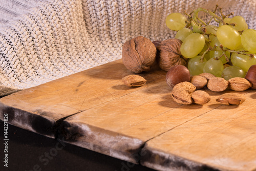 A nice image of mixed nuts and grapes on a wooden surface.