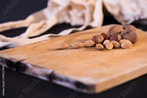 A nice image of mixed nuts and grapes on a wooden surface.