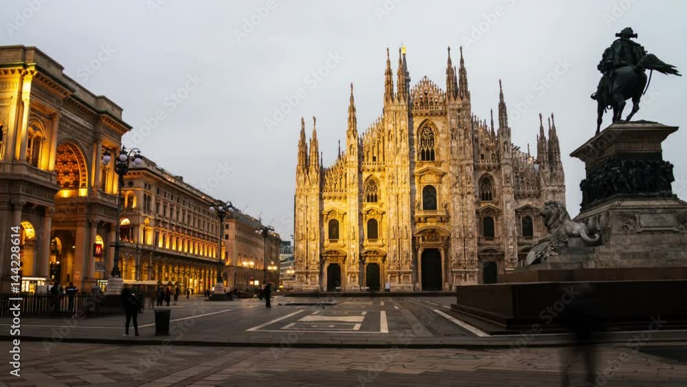 Milan, Italy. Cathedral of Milan, Italy at sunrise - famous landmark in the city. Motion blurred people, illuminated Gallery entrance, cloudy sky in the morning. Time-lapse Milan, Italy. Cathedral of Milan, Italy at sunrise - famous landmark in the city. Motion blurred people, illuminated Gallery entrance, cloudy sky in the morning. Time-lapse