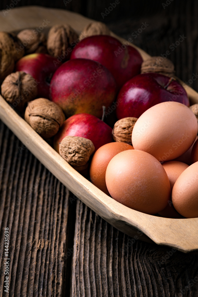 Wooden bowl with apple, eggs and walnut Wooden bowl with apple, eggs and walnut