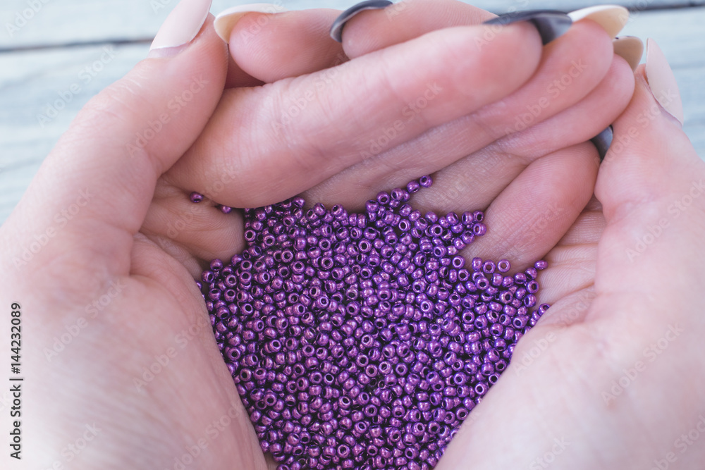 Purple seed beads in the hands of a girl Purple seed beads in the hands of a girl