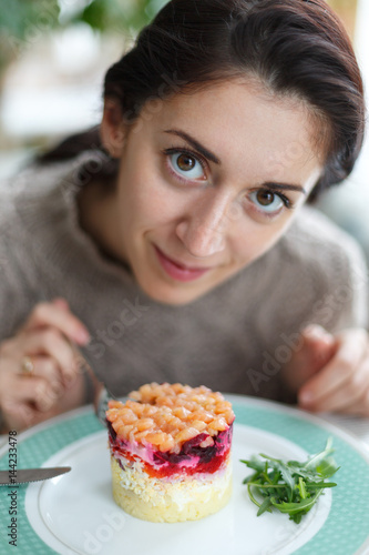 Beautiful young brunette woman eating salad.