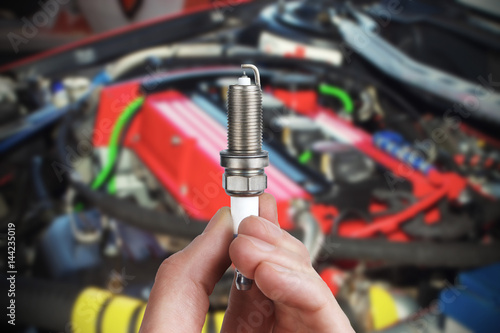 Mechanic holds a spare part spark plug in his hand. Auto part spark plug close-up.