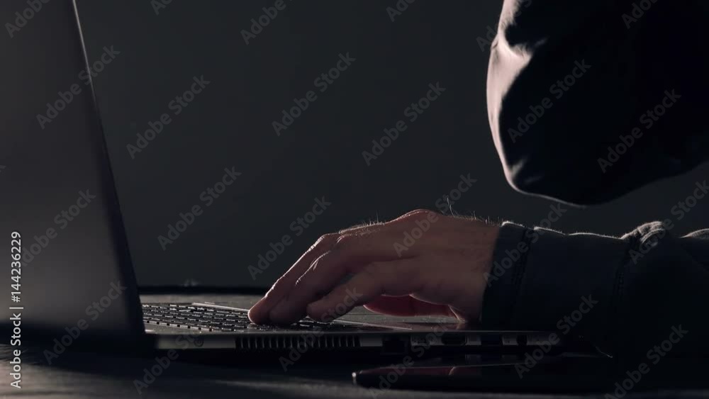 Computer programmer and hacker hands typing laptop keyboard, close up low key with selective focus Computer programmer and hacker hands typing laptop keyboard, close up low key with selective focus