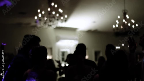 Group of silhouetted people dancing in a dark banquet hall for a wedding reception