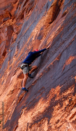 Mann klettert auf Felswand in Moab / USA