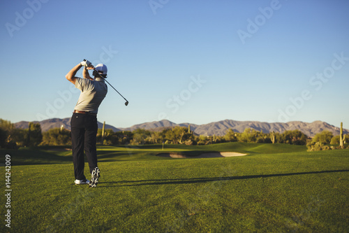Rear view of man playing golf against clear blue sky photo
