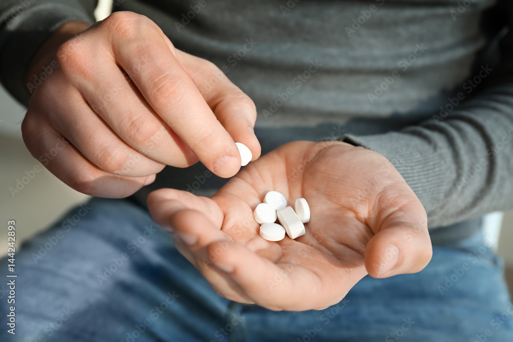 Young man with pills, closeup