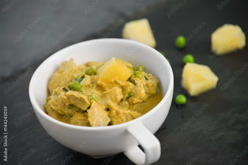 Pineapple, pea and pork stew on black stone background Pineapple, pea and pork stew on black stone background