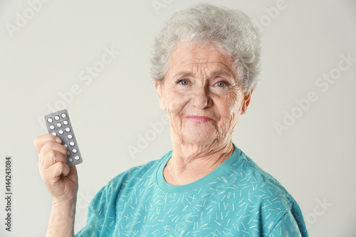 Elderly woman with pills on...