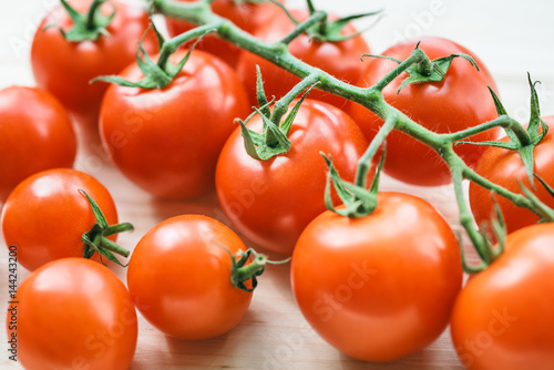 Macro photo of ripe tomatoes on a green branch. Tomatoes on a light wooden table